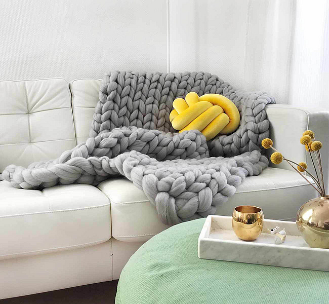 Grobmaschig gestrickte graue Decke von adorist in Kombination mit rundem gelben adorist-Kissen